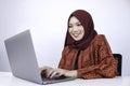 Young Islam woman is sitting enjoy and smiling when working on laptop on white background