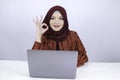 Young Islam woman is smile and happy when working on a laptop with ok hand sign