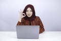 Young Islam woman is smile and happy when working on a laptop with ok hand sign