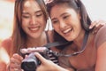 Young asian joyful woman and friend in summer fashion dress sitting and looking photo after shooting by camera in amusement park Royalty Free Stock Photo