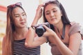 Young asian joyful woman and friend in summer fashion dress sitting and looking photo after shooting by camera in amusement park Royalty Free Stock Photo