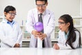 Young Asian kids wearing white scientist gown and do chemical test tube while study, learning in science classroom with teacher.