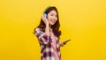 Young Asian lady wearing wireless headphones listening to music from smartphone with cheerful expression in casual clothing and Royalty Free Stock Photo
