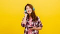 Young Asian lady wearing wireless headphones listening to music from smartphone with cheerful expression in casual clothing and Royalty Free Stock Photo