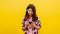 Young Asian lady wearing wireless headphones listening to music from smartphone. Royalty Free Stock Photo