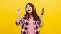 Young Asian lady wearing wireless headphones listening to music from smartphone with cheerful expression. Royalty Free Stock Photo