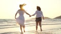 Young Asian lesbian couple running on beach. Beautiful women friends happy relax having fun on beach near sea when sunset in Royalty Free Stock Photo