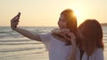 Young Asian lesbian couple using smartphone taking selfie near beach. Beautiful women lgbt couple happy relax enjoy love moment Royalty Free Stock Photo