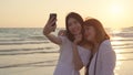 Young Asian lesbian couple using smartphone taking selfie near beach. Beautiful women lgbt couple happy relax enjoy love moment Royalty Free Stock Photo