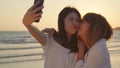 Young Asian lesbian couple using smartphone taking selfie near beach. Beautiful women lgbt couple happy relax enjoy love moment Royalty Free Stock Photo