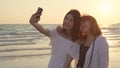 Young Asian lesbian couple using smartphone taking selfie near beach. Beautiful women lgbt couple happy relax enjoy love moment Royalty Free Stock Photo