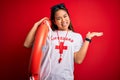 Young asian lifeguard girl wearing t-shirt with red cross using whistle holding orange float very happy and excited, winner