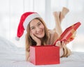 A young asian long brown hair female wearing red and white santa hat lying down on white sheet bed crossing her legs open cover of Royalty Free Stock Photo