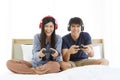 Young Asian Lovely Couple Playing Video Game console on bed in Bedroom. Spends time together. Royalty Free Stock Photo