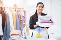 Asian woman smiling and holding ironed things.