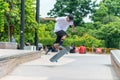 Young asian male boy skater displaying board skating skills outdoor in skatepark