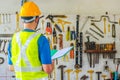 Young Asian male engineer or architect holding files wearing protective safety helmet near the many different rusty old tools