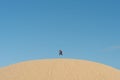 Young asian male jumping high on a sand dunes against clear blue sky Royalty Free Stock Photo