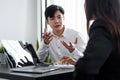 Young asian male mentor coach worker talking to female coworker teaching intern having business conversation with Royalty Free Stock Photo