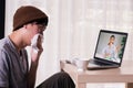 Young Asian male patient with sickness using laptop to video call conferencing with doctor at home. Medical