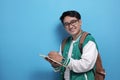 Young Asian male student wearing green baseball jacket writing on book Royalty Free Stock Photo