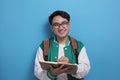 Young Asian male student wearing green baseball jacket writing on book Royalty Free Stock Photo