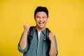 Young Asian male tourists are very happy and excited with hands raising their fists successfully in yellow background studio