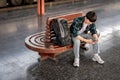 A young Asian male traveler is using his smartphone while waiting for his train at a railway station Royalty Free Stock Photo
