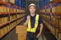 Young asian male worker wearing helmet using talki walki in modern warehouse