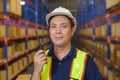 Young asian male worker wearing helmet using talki walki in modern warehouse