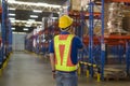 Young asian male worker wearing helmet using talki walki in modern warehouse