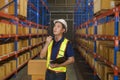 Young asian male worker wearing helmet using talki walki in modern warehouse