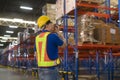 Young asian male worker wearing helmet using talki walki in modern warehouse