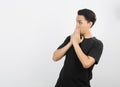 Young asian man with black shirt excited with hands covering mouth isolated on white background.