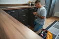 Young man sat down at kitchen cabinet, next to toolbox