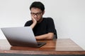 Young Asian man is boring and lazy in the front the laptop. Indonesia Man wear black shirt grey background