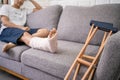 Young Asian man with a broken leg sitting on the sofa. Close up of the crutch Royalty Free Stock Photo