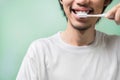 Young asian man brushing teeth with a pink toothbrush wear white t-shirt in morning on green background Royalty Free Stock Photo