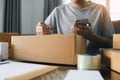 Young asian man business owner hands writing address on cardboard box at workplace or home office