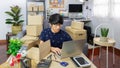 Young Asian man business owner working at home Start up for Business Online, working with laptop for checking, packaging delivery