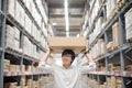 Young Asian man carry paper box over head in warehouse Royalty Free Stock Photo