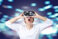 Young asian man in casual white wearing and holding VR glasses by hands looking up above feeling excited and amazed Royalty Free Stock Photo