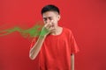 Young Asian man close his nose for bad smell, on red color Royalty Free Stock Photo