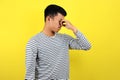 Young Asian man close his nose for bad smell, isolated on yellow Royalty Free Stock Photo