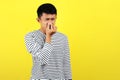 Young Asian man close his nose for bad smell, isolated on yellow Royalty Free Stock Photo