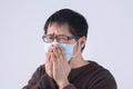 Young Asian man is coughing, feeling unwell, vomit sick with wearing a medical blue face mask isolated on white background, close Royalty Free Stock Photo