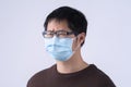 Young Asian man is coughing, feeling unwell, vomit sick with wearing a medical blue face mask  on white background, close Royalty Free Stock Photo