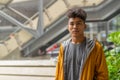 Young Asian man with curly hair thinking in the city outdoors with rain