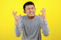 Young Asian man doing angry gesture, annoyed, and emotional, isolated on yellow