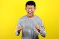 Young Asian man doing angry gesture, annoyed, and emotional, isolated on yellow